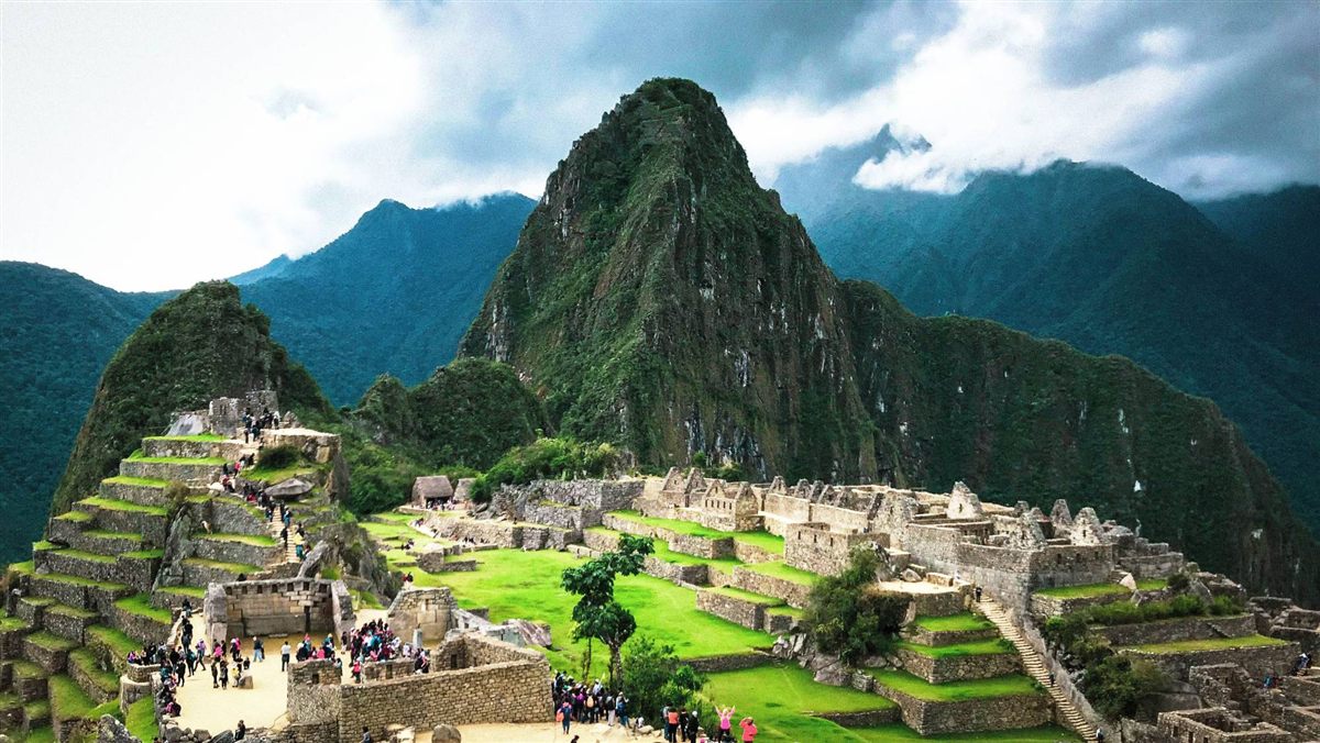 Machu Picchu: ruinas incas sobre terrazas verdes, con el Huayna Picchu detrás entre nubes